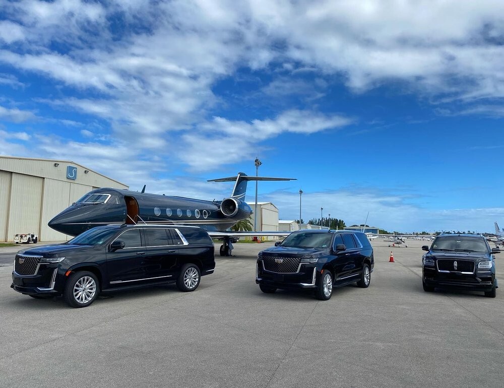 Private jet with luxury SUVs on tarmac